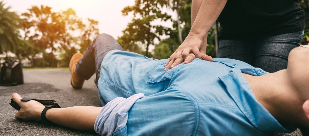 Man lying on the road having CPR being performed on him