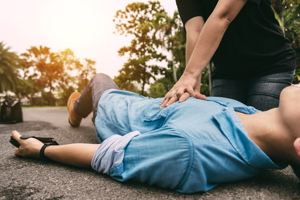 Man lying on the road having CPR being performed on him